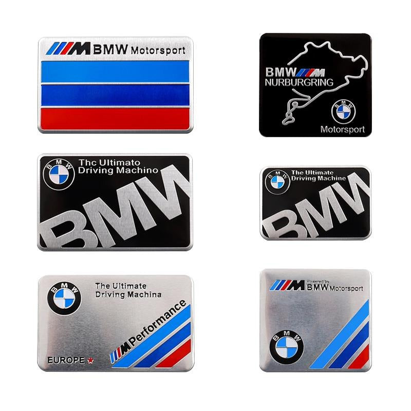 Collection of BMW aluminum badges including Nurburgring and Ultimate Driving Machine designs