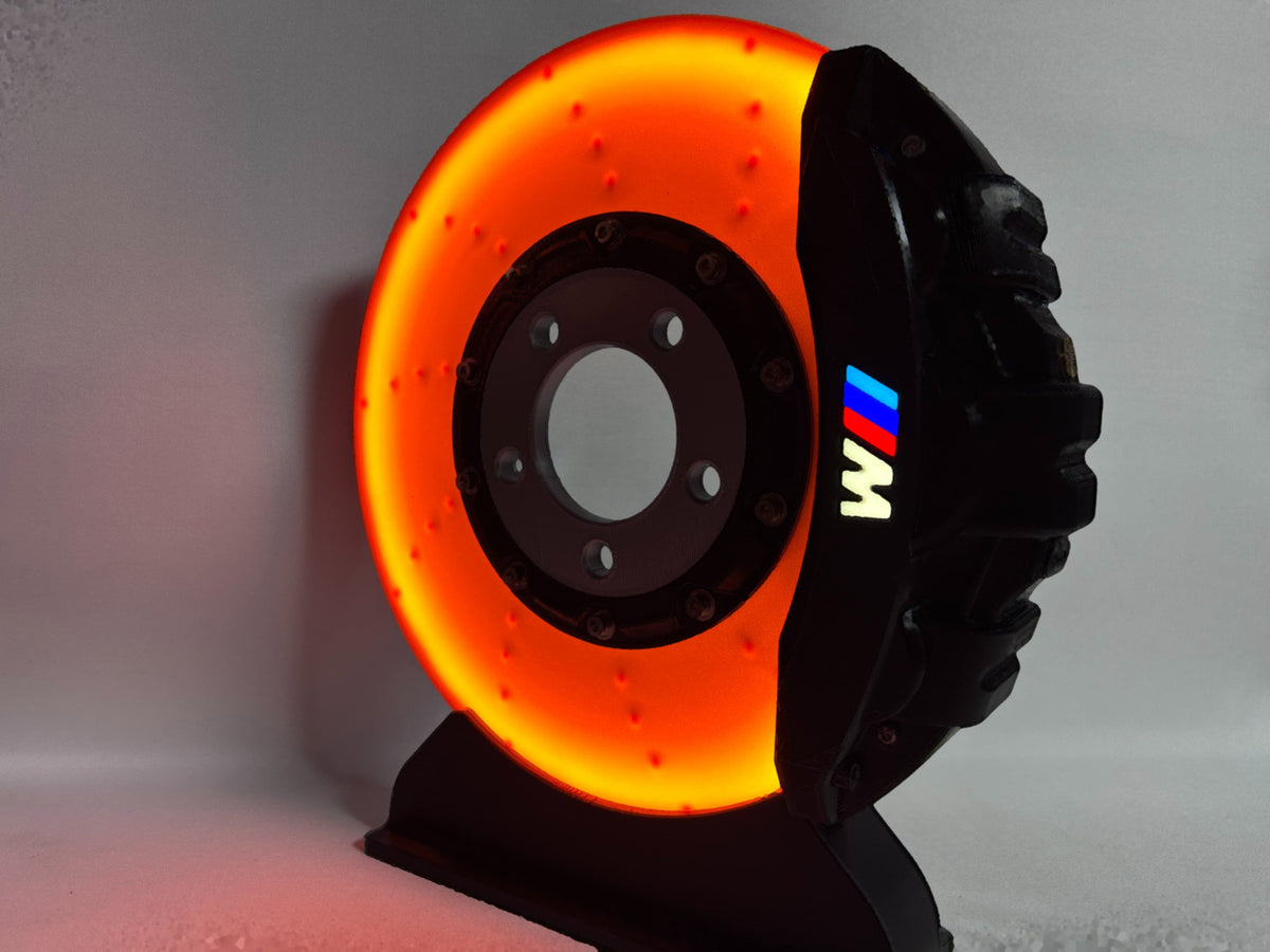 BMW M brake disc LED night light, black caliper, close-up glowing