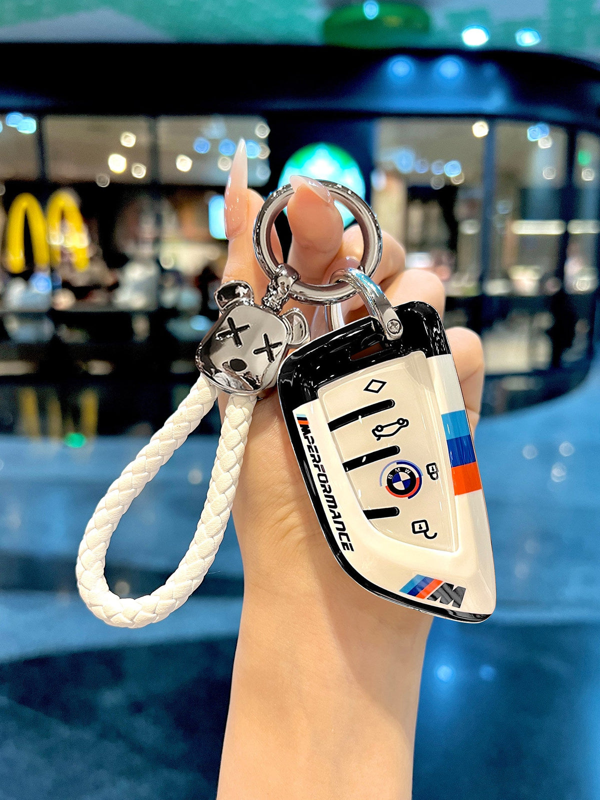 BMW white TPU key fob case with braided rope keychain held in hand