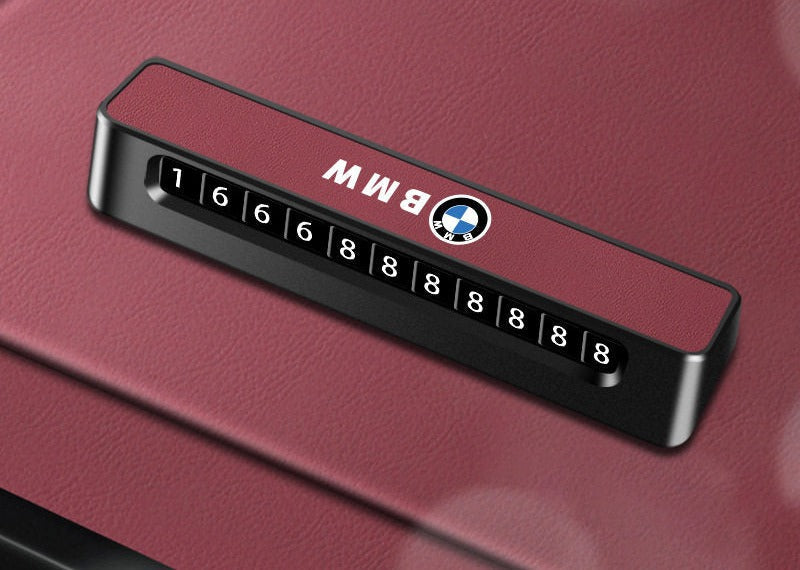 BMW parking number plate with leather-textured design on red dashboard trim