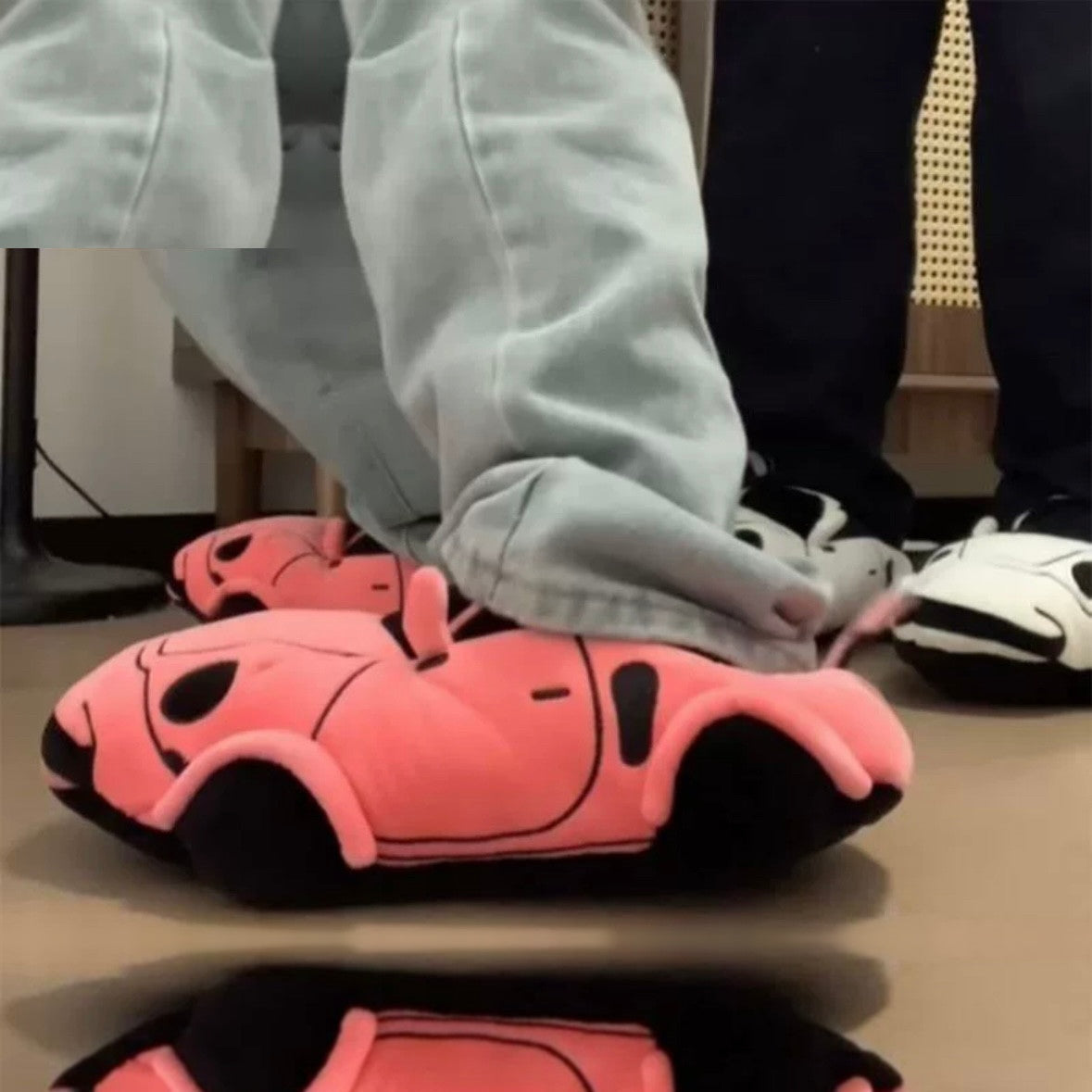 Person wearing pink sports car plush slippers indoors