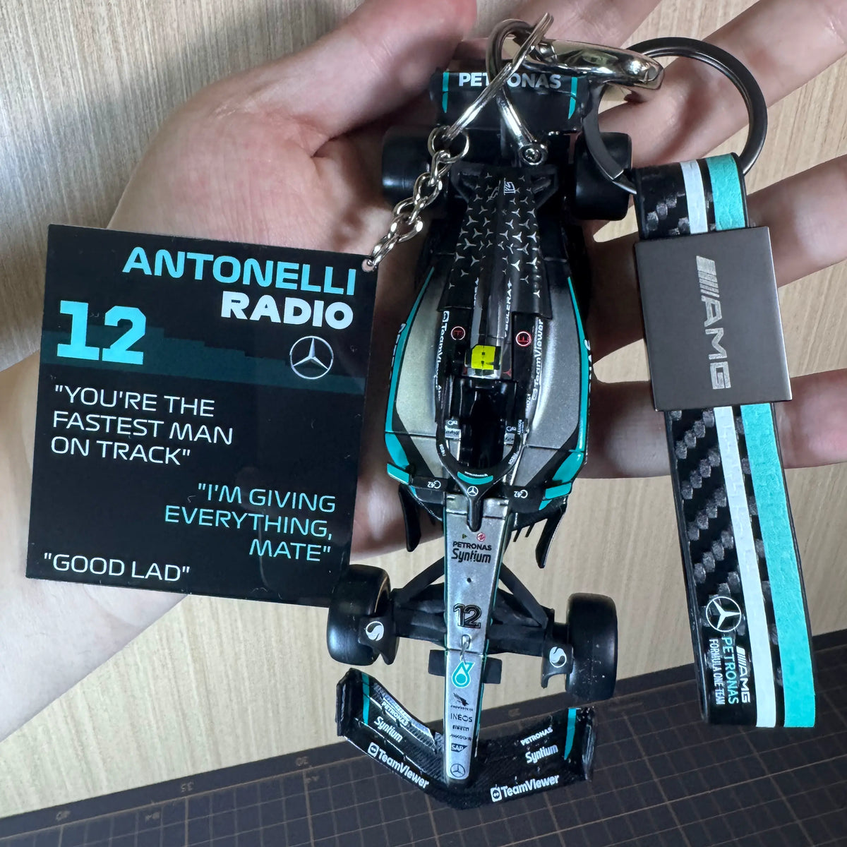 Mercedes-AMG F1 car keychain with Antonelli radio pendant and AMG strap in hand