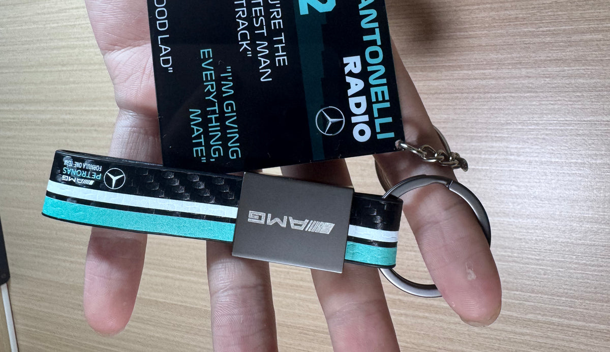 Antonelli radio acrylic pendant and AMG strap keychain held in hand
