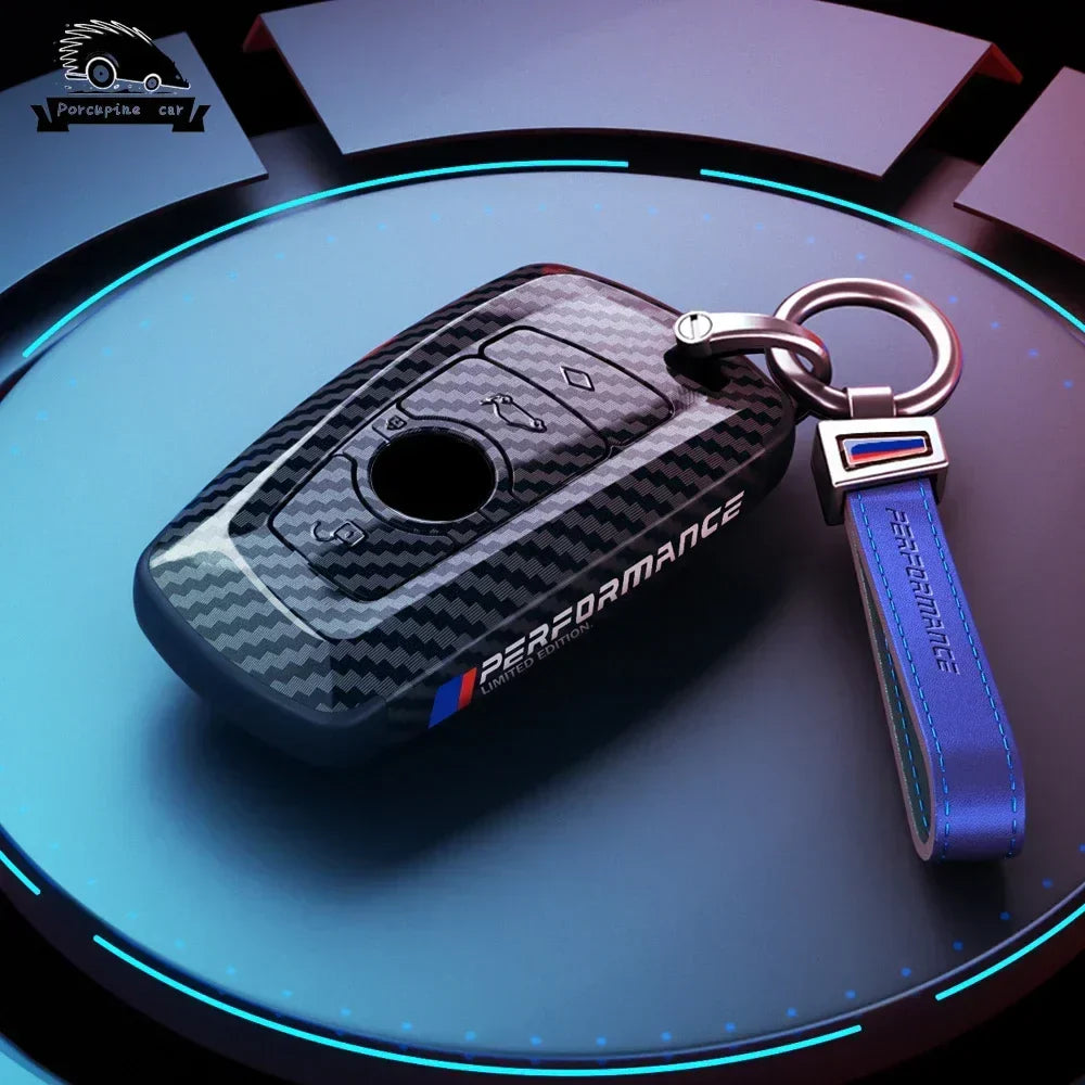 BMW dark carbon key case with blue M keychain, top view