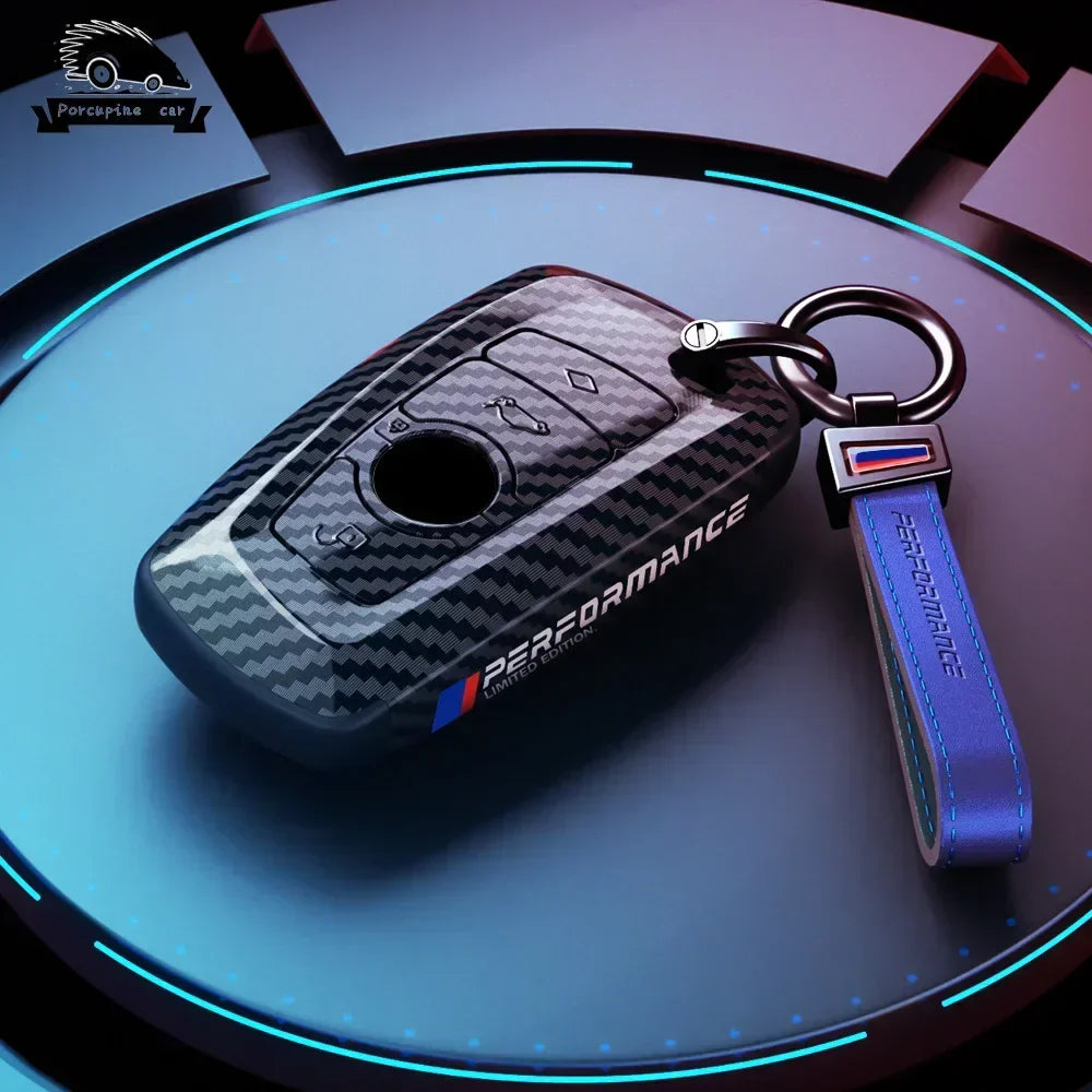 BMW dark carbon key case with blue M keychain, side view