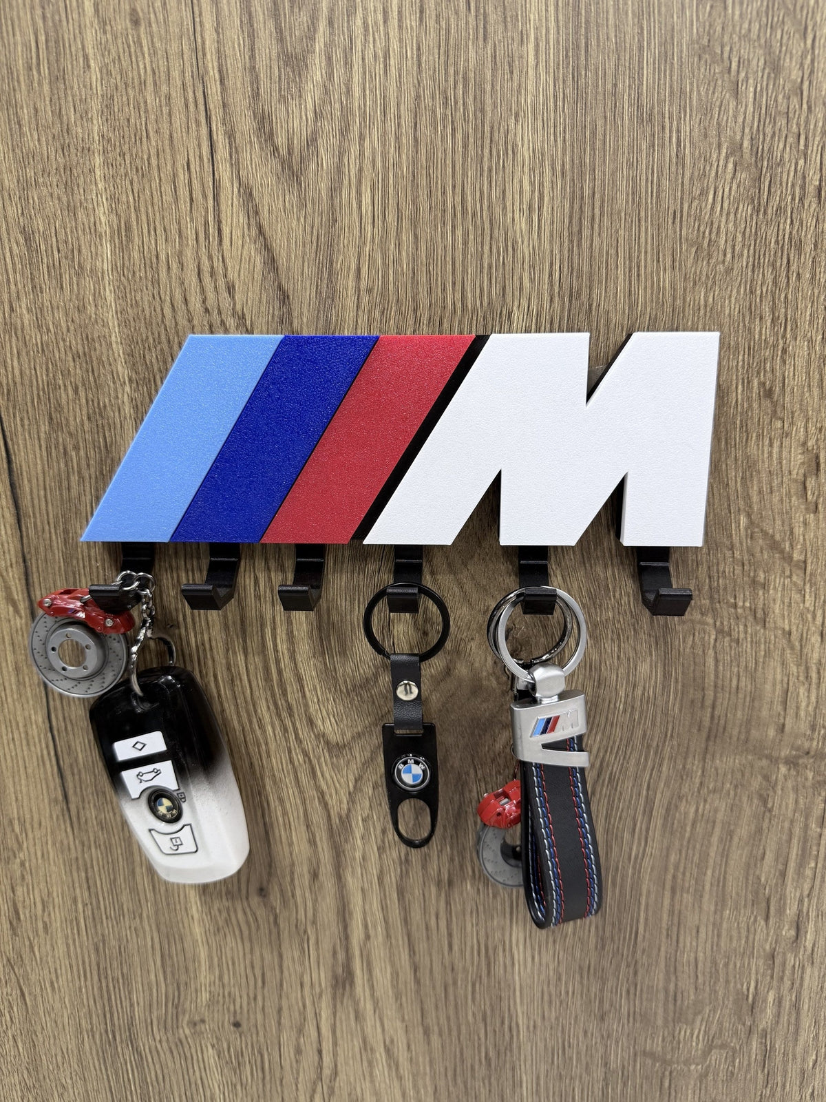 BMW M Stripe wall key holder with BMW keys and keychains hanging on 6 hooks